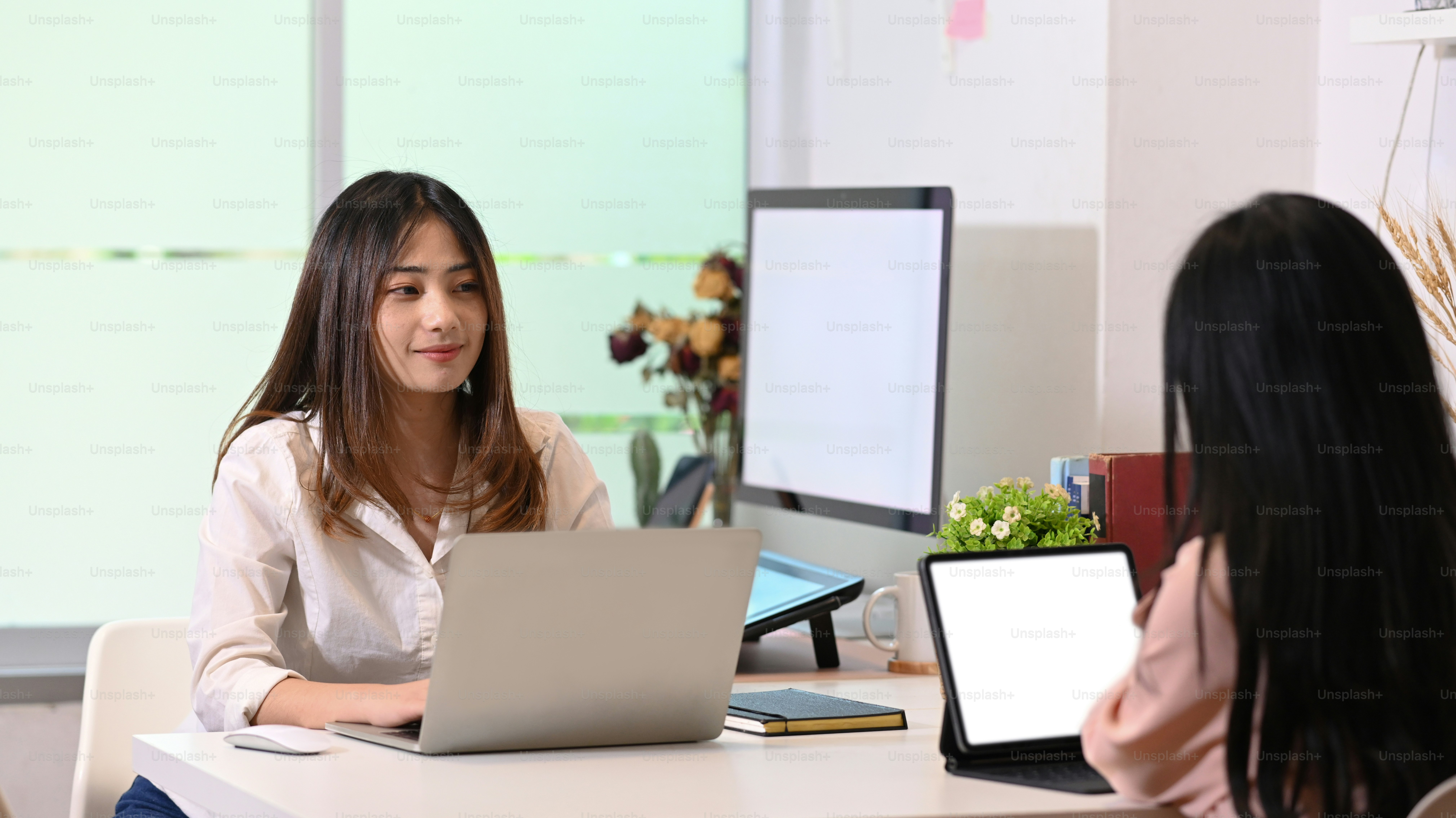 Two young designer working and sitting together in creative office.