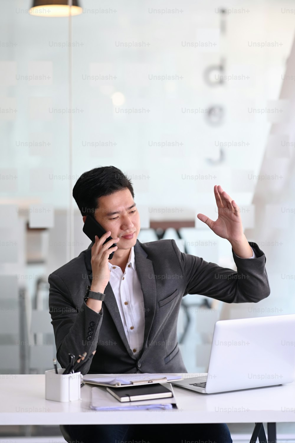 Portrait of handsome businessman in a phone call talking and explaining information while sitting in office.