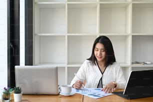 Businesswoman using laptop analyzing income and budget.