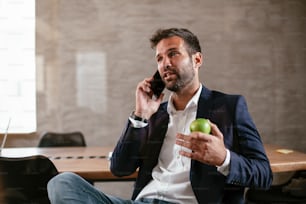Empresário na sala de conferências usando o telefone. Empresário bonito falando ao telefone.