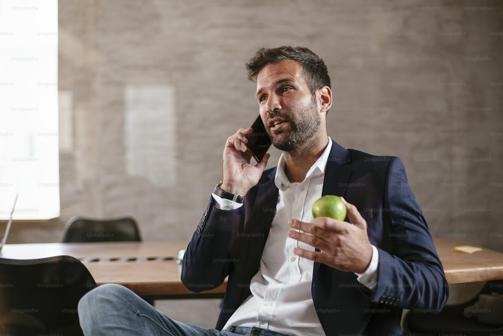 Businessman in the conference room using the phone. Handsome businessman talking to the phone.