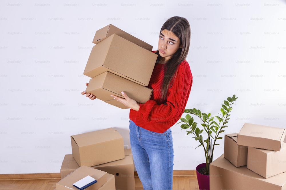 Una mujer joven acaba de mudarse a un nuevo apartamento vacío desempacando y limpiando - reubicación. Joven que lleva cajas de cartón en su nuevo hogar. Mudanza.