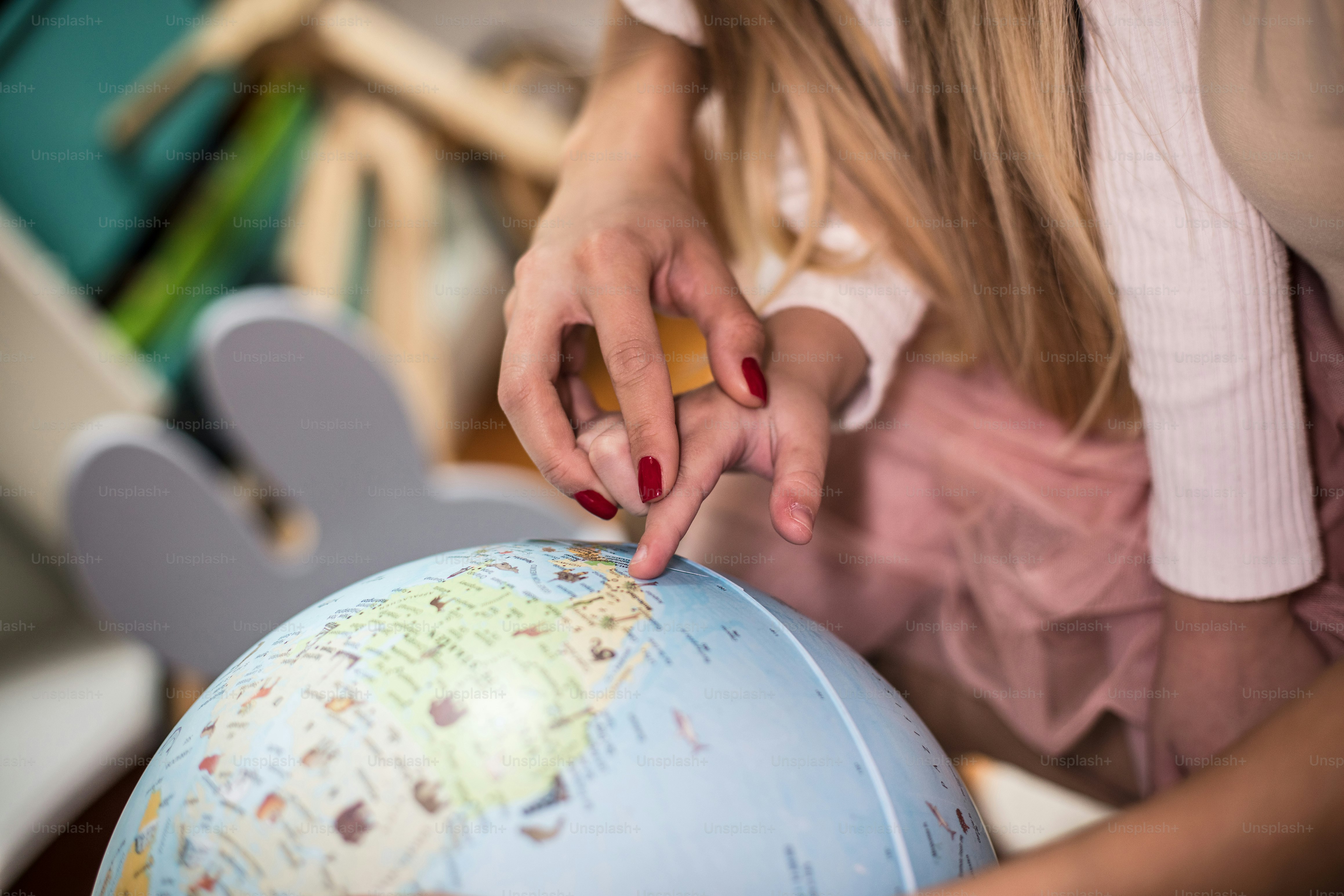 Mother and daughter learning geography on a world globe. Focus is on ...