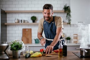 Portrait of handsome man in kitchen. Young man preparing salad.