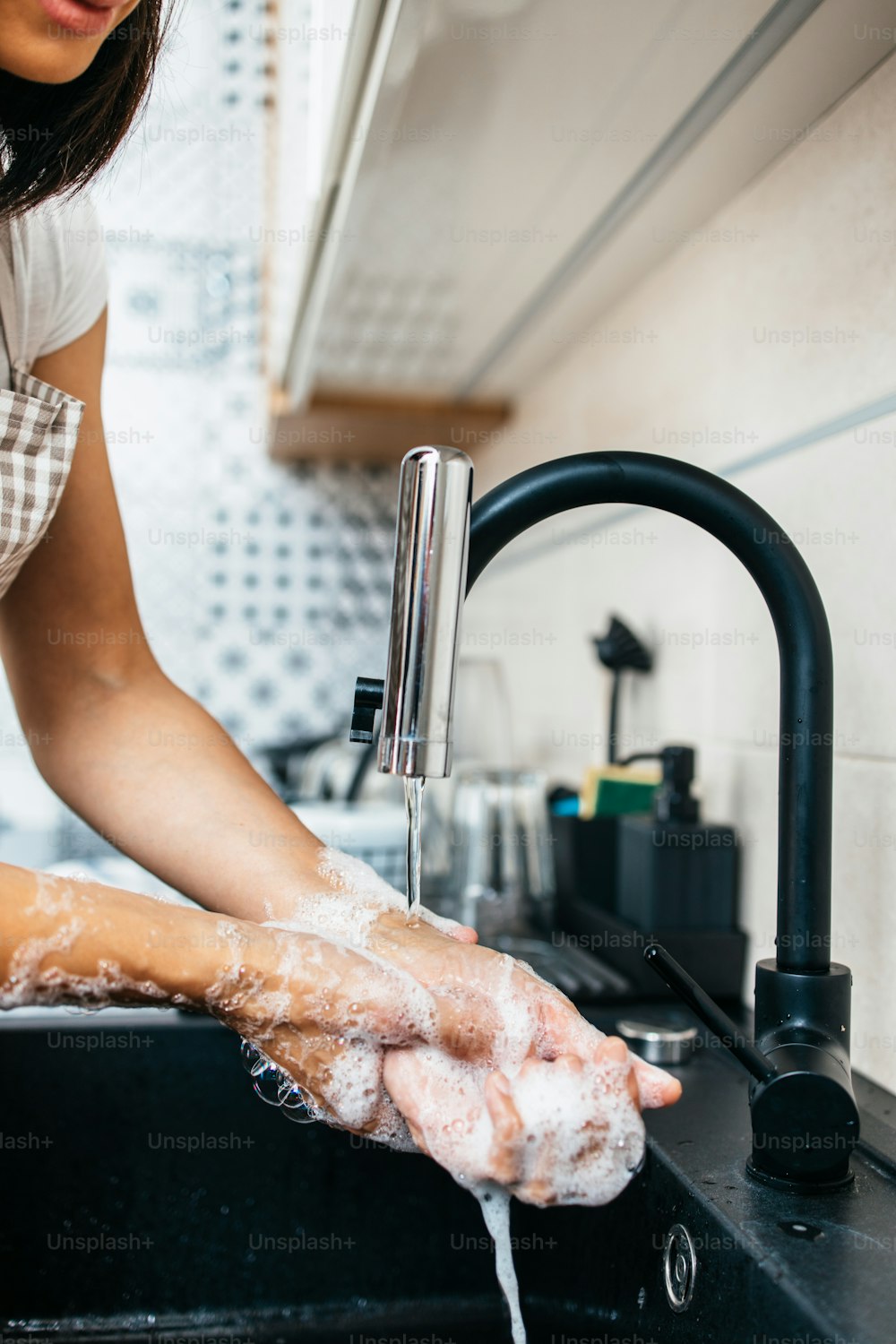 Young adult woman washing her hands on kitchen sink. Household and home and personal hygiene routine.