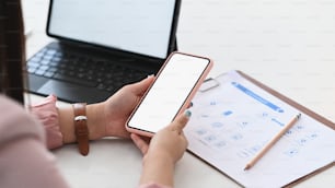 Vista de perto da empresária que trabalha com tablet e usando o telefone celular na mesa do escritório.