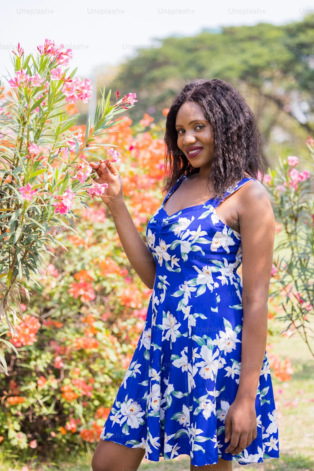 Content Black Woman Smelling Flowers in Park.