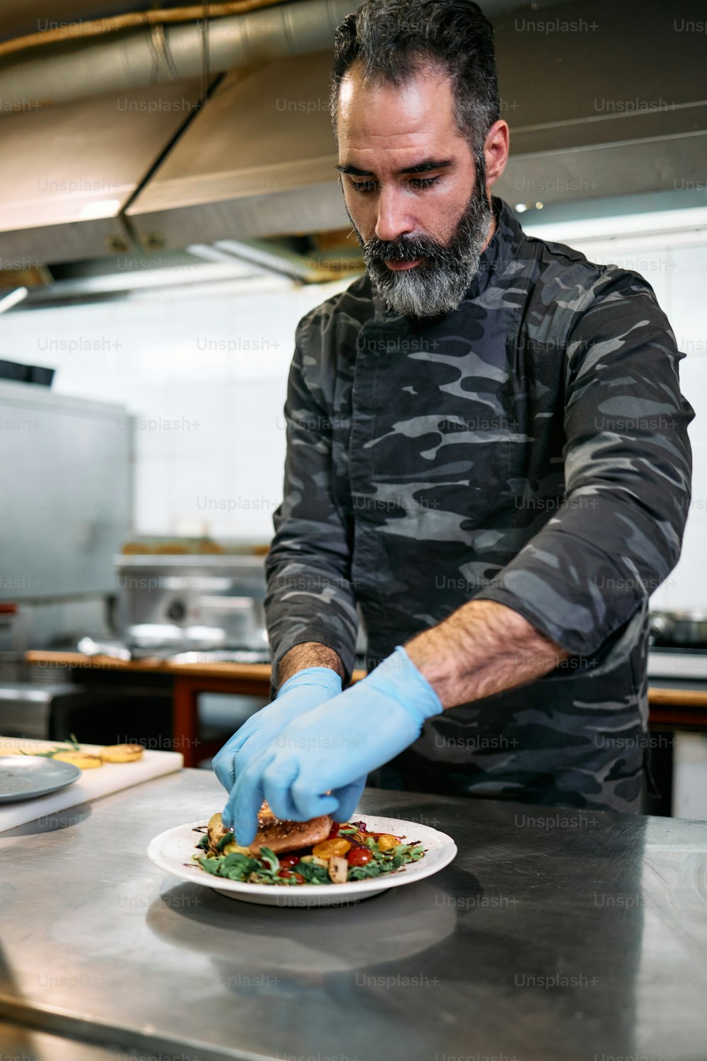 Professional military base chef or cook preparing delicious tasty meal with fresh salmon fish and salad.