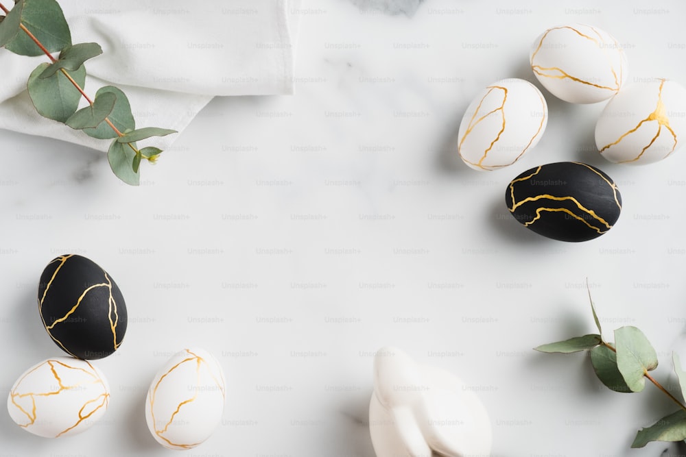Composición plana de Pascua de lujo con huevos negros y dorados, hojas de eucalipto, conejo conejito, toalla sobre mesa de mármol. Concepto de feliz Pascua. Vista superior.