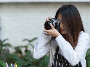 Portrait of female barista enjoy her hobby with taking photo with digital camera in cafe