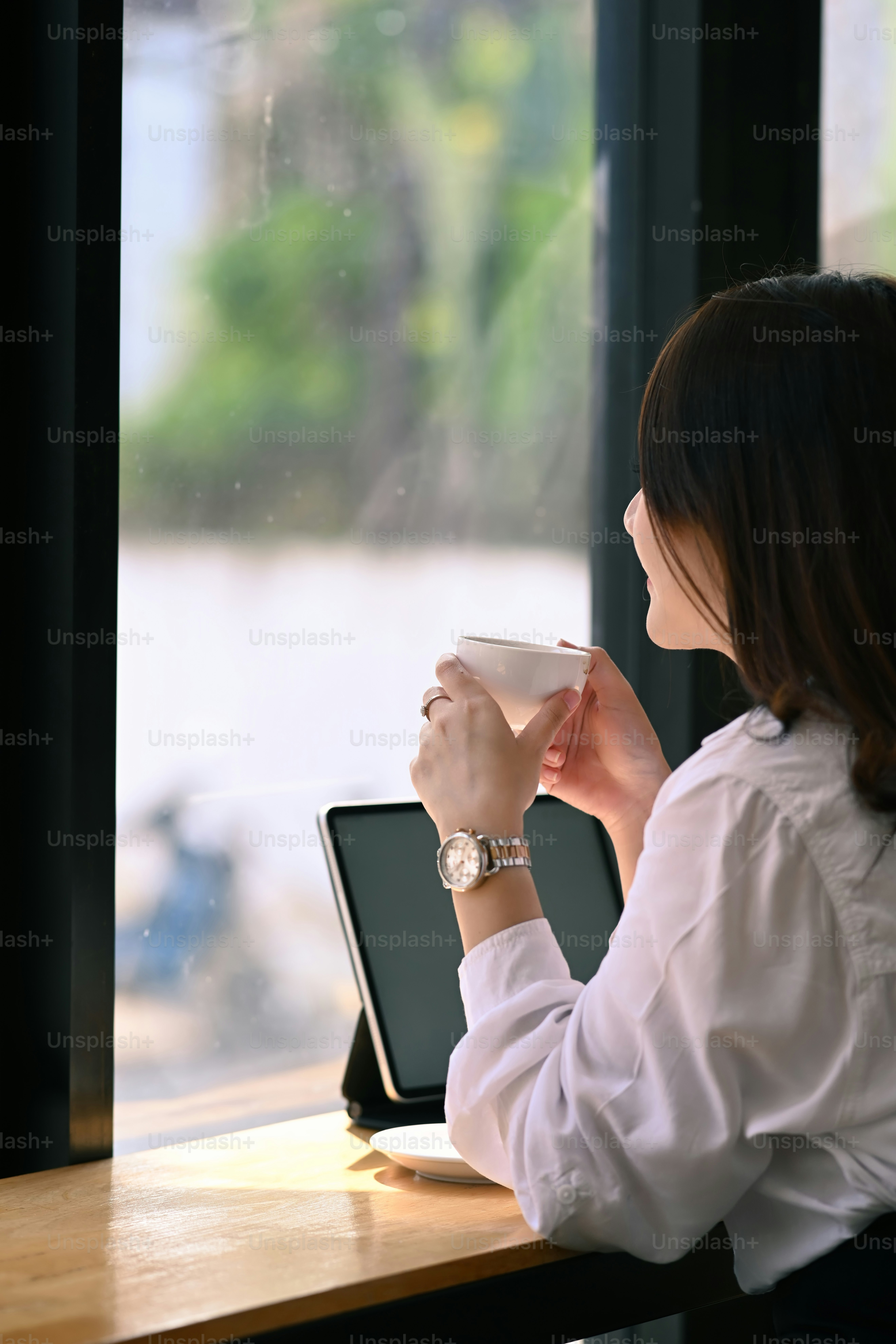 Les jeunes femmes aiment boire du café le matin tout en étant assise près de la fenêtre au bureau.