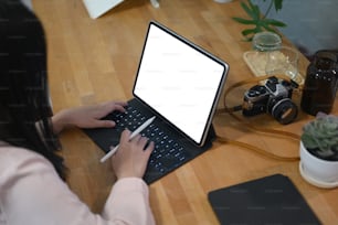 Rear view of young woman photographer working with tablet computer on wooden table.