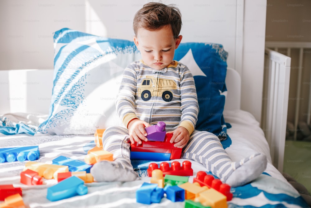 Cute baby toddler playing building with learning toy stacking blocks at home. Early age education. Kids hand brain and fine motor skills development. Logic activity for preschoolers.