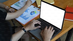 Cropped shot of businesspeople working on laptop computer and analyzing documents at meeting room.