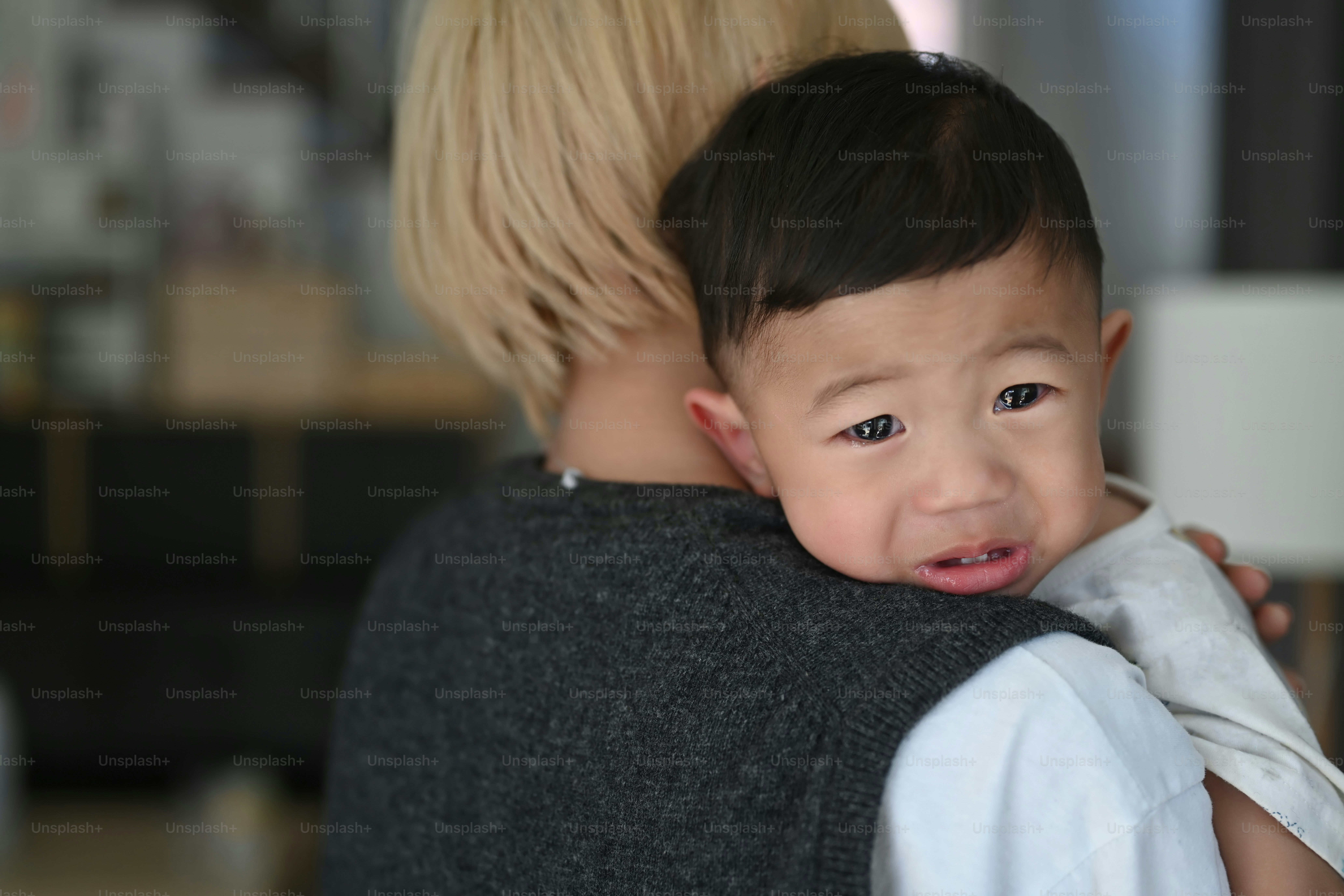 Young mother holding  her crying son at home.
