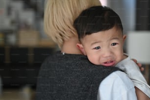 Young mother holding  her crying son at home.