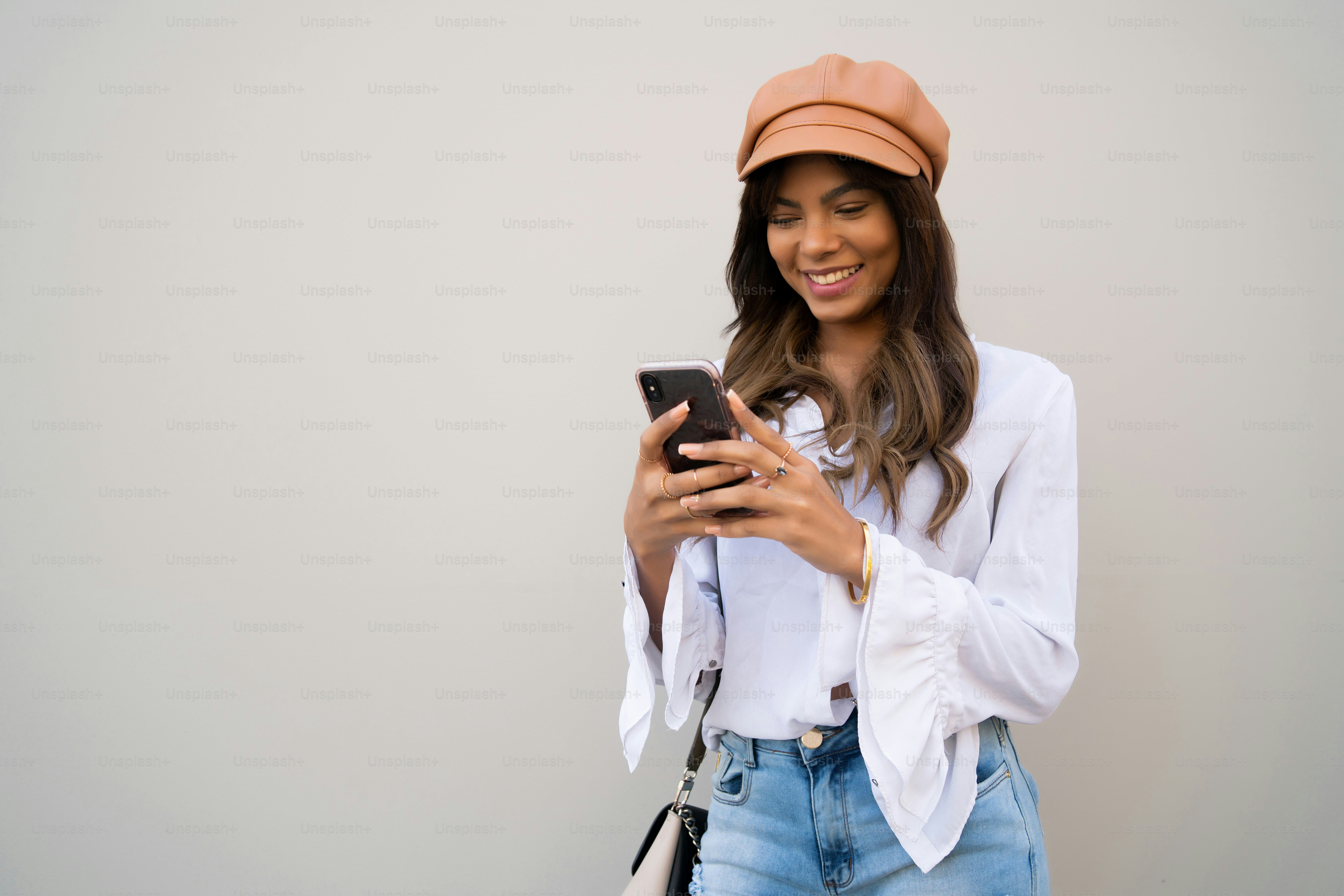 Portrait of young woman using her mobile phone while standing outdoors on the street. Urban and communication concept.