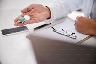 Cropped photo of a male optical dispenser showing a plastic lens case on his palm