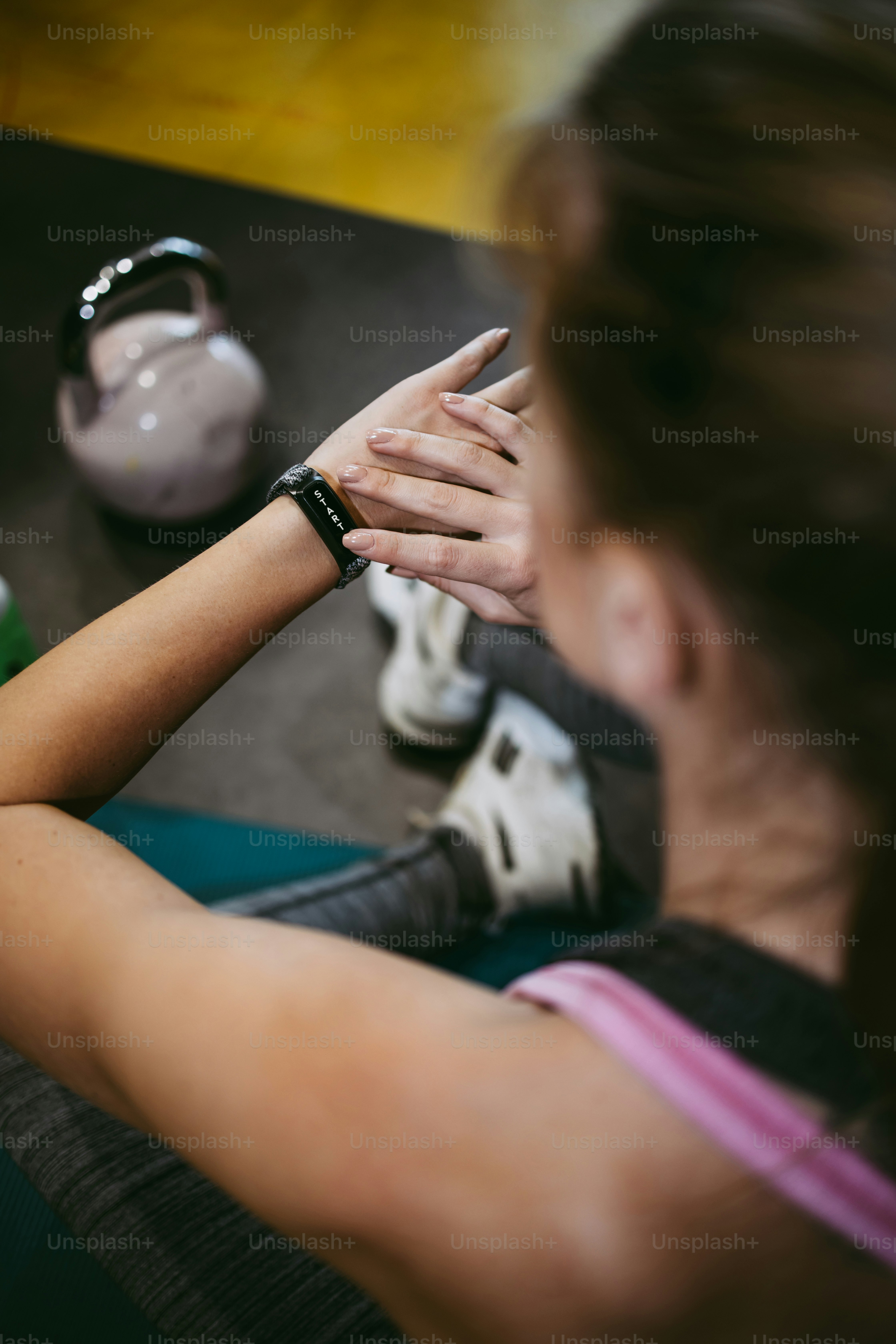 Jeune femme en forme et attrayante s’entraînant et se reposant dans une salle de sport moderne et écoutant de la musique avec des écouteurs Bluetooth et un téléphone intelligent.
