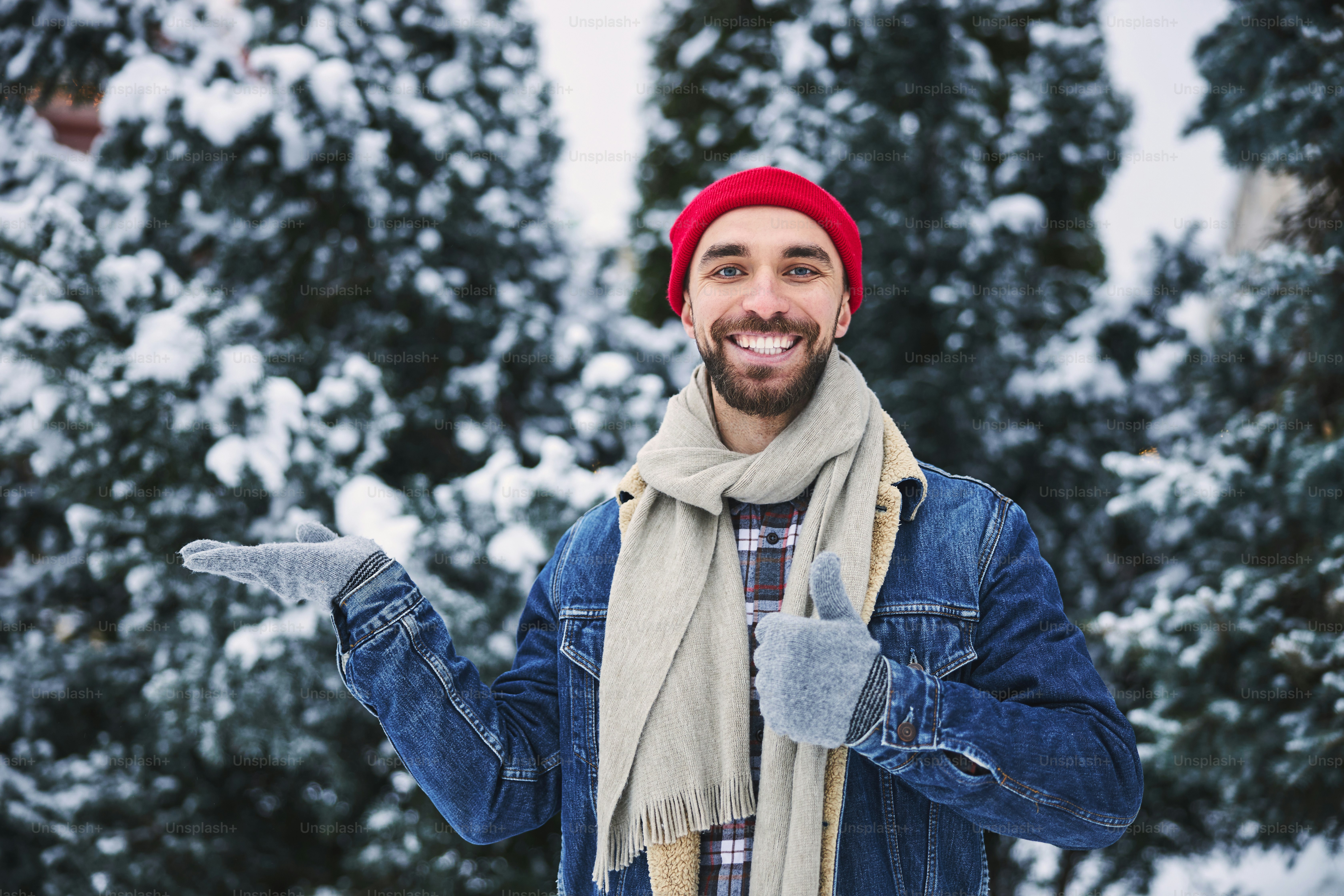 Waist up portrait of joyful young guy enjoying cold snowy day while spending time in nature