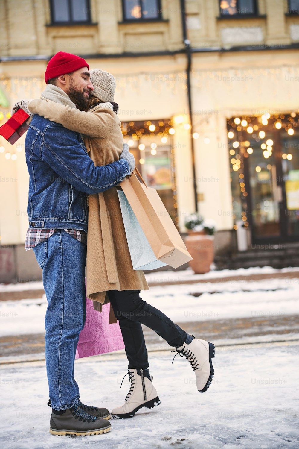 행복한 여자는 크리스마스 휴일에 야외에서 선물을 교환하는 동안 사랑하는 남자를 껴안고 있다