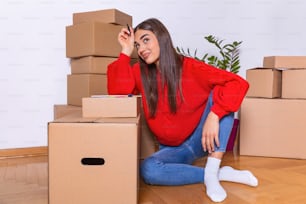 A young beautiful women makes her notes and plans in her new flat,apartment. Young woman packing cardboard box. Moving house concept.