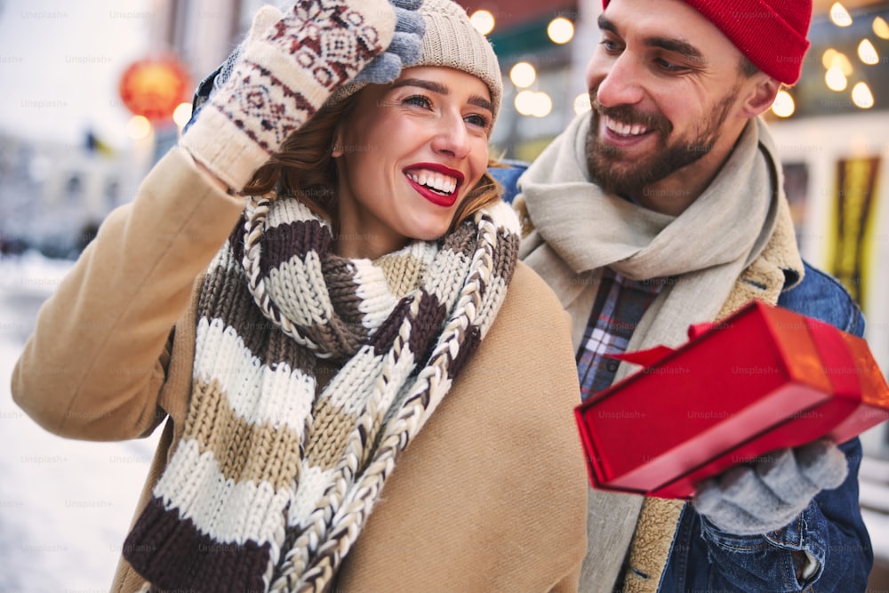 Cheerful woman is happy of getting New Year gift from beloved man in winter outdoors