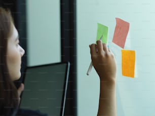 Cropped shot of female office worker working with digital tablet and sticky note with idea in office room