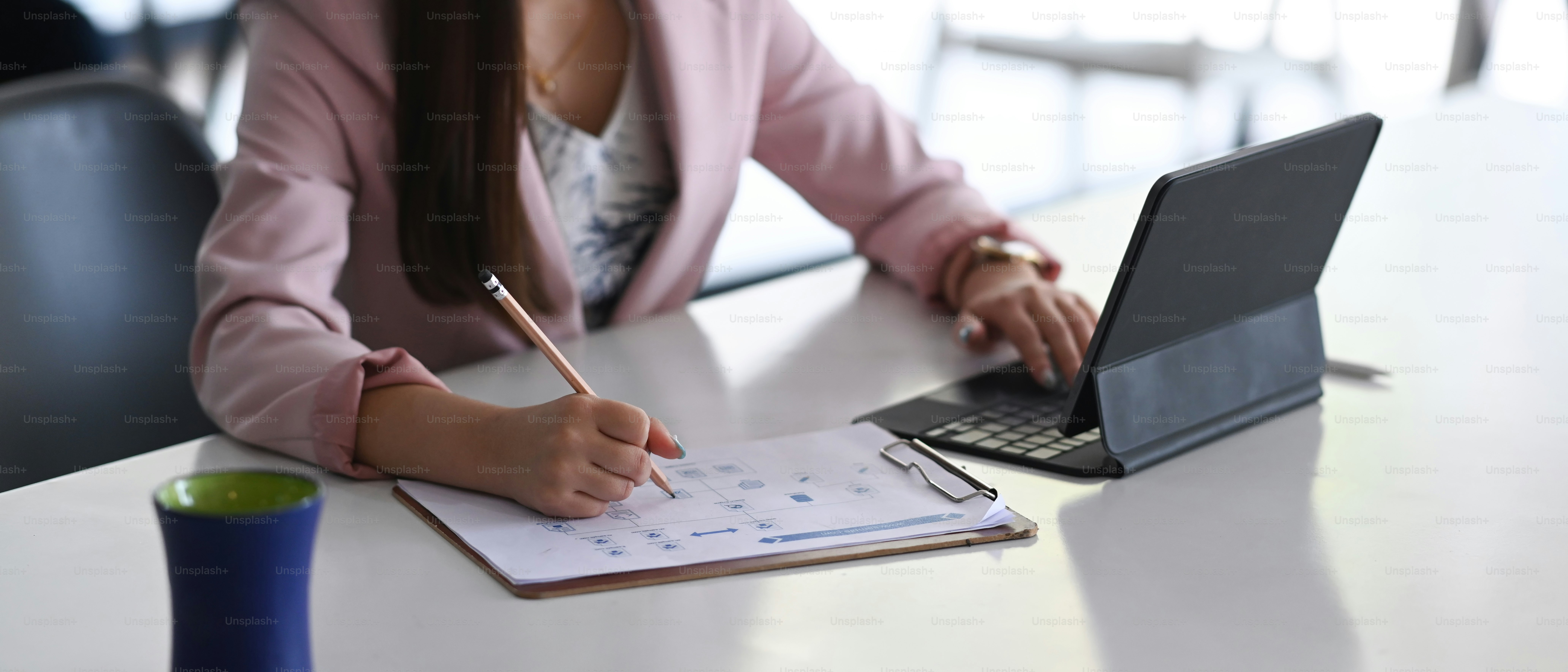 Cropped shot of businesswoman working with tablet computer and writing ...