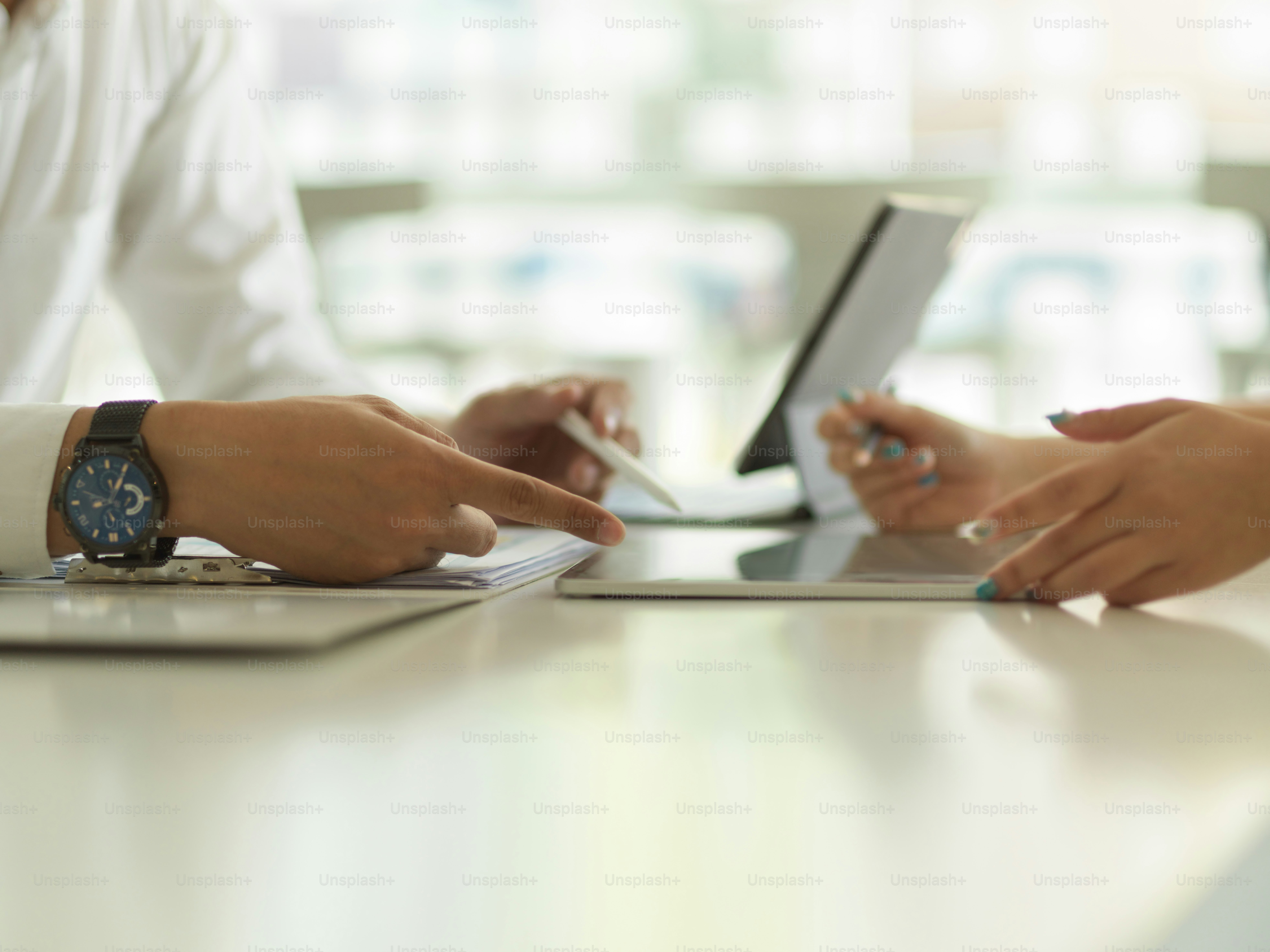 Side view of businesspeople hands working with digital tablet and document file on the table