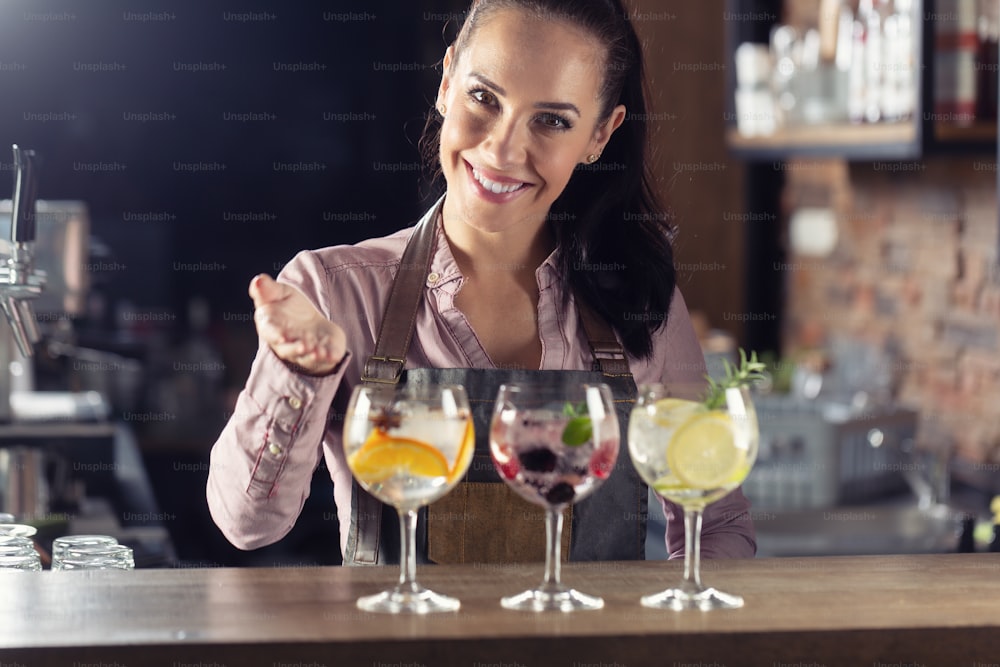 Bartender offers selection of various gin tonic drinks served on a bar.