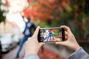 Una giovane coppia con smartphone che realizza video per i social media all'aperto per strada.
