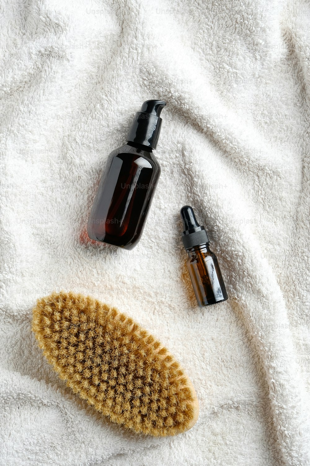 Dry brush and essential oils on white towel in bathroom. Body care, cellulite treatment concept.