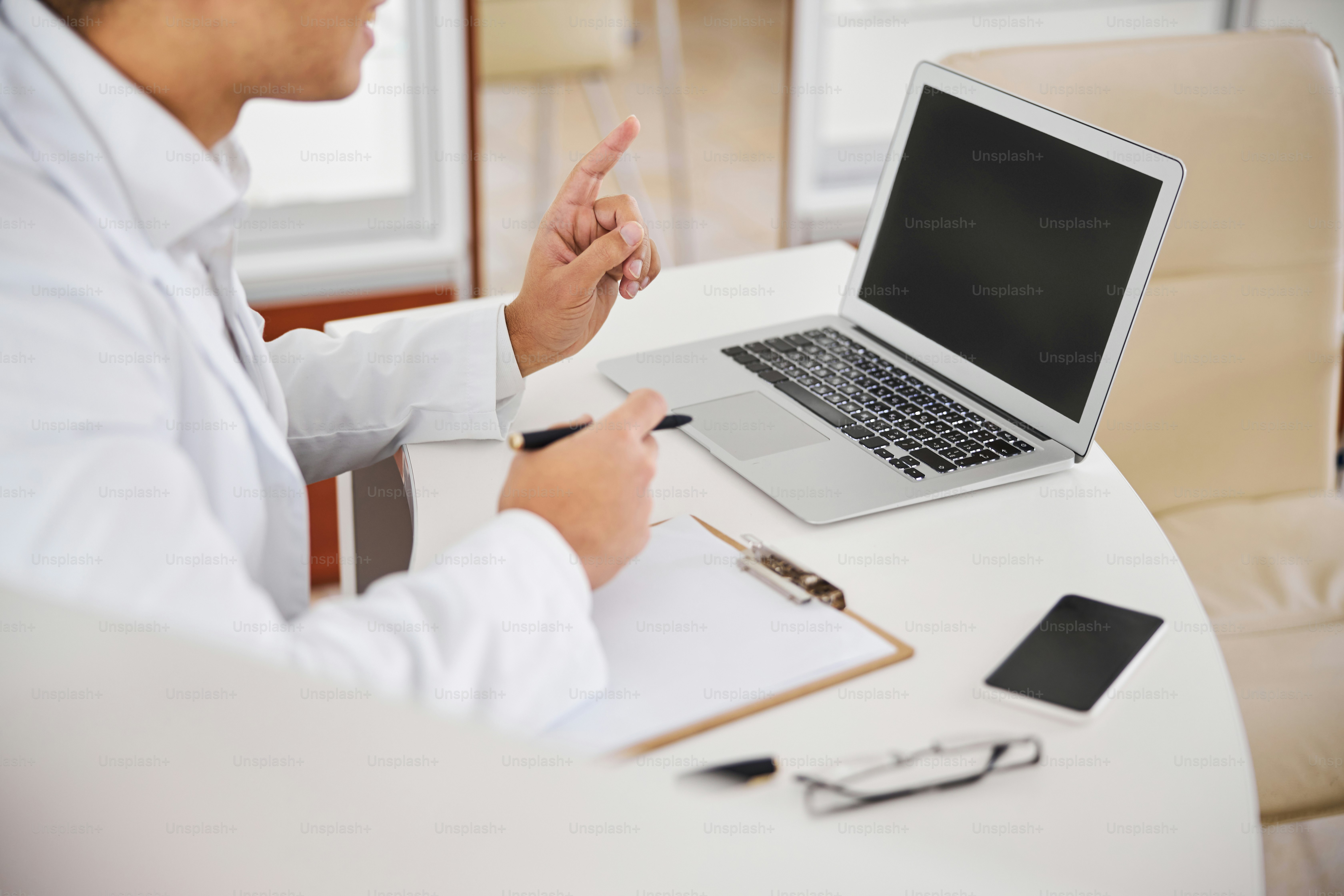 Cropped photo of a smiling pleased optometrist in a lab coat writing a spectacle prescription