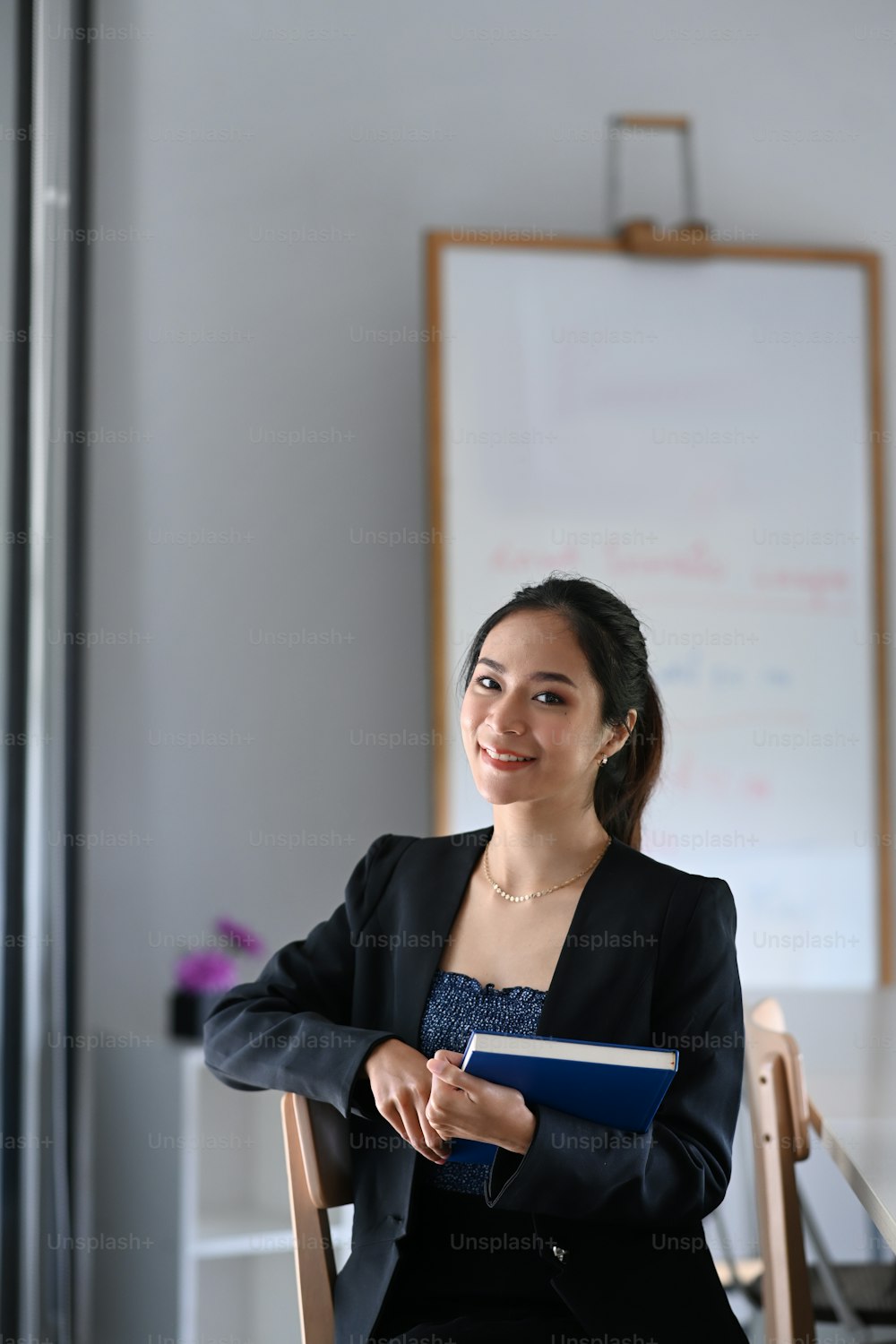 Portrait of attractive businesswoman in suit hold documents folder while sitting in modern office.