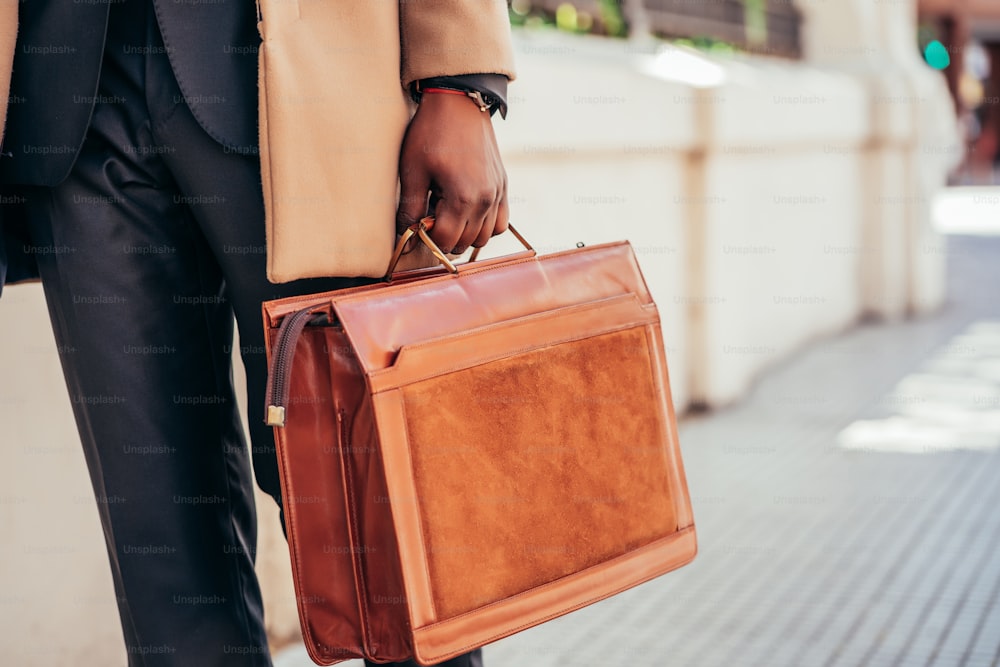 Business man holding briefcase while walking outdoors on the street. Business concept.