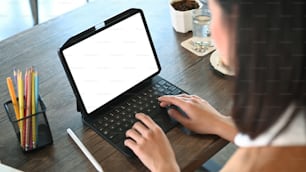 Cropped shot of young woman designer typing on keyboard of digital tablet.