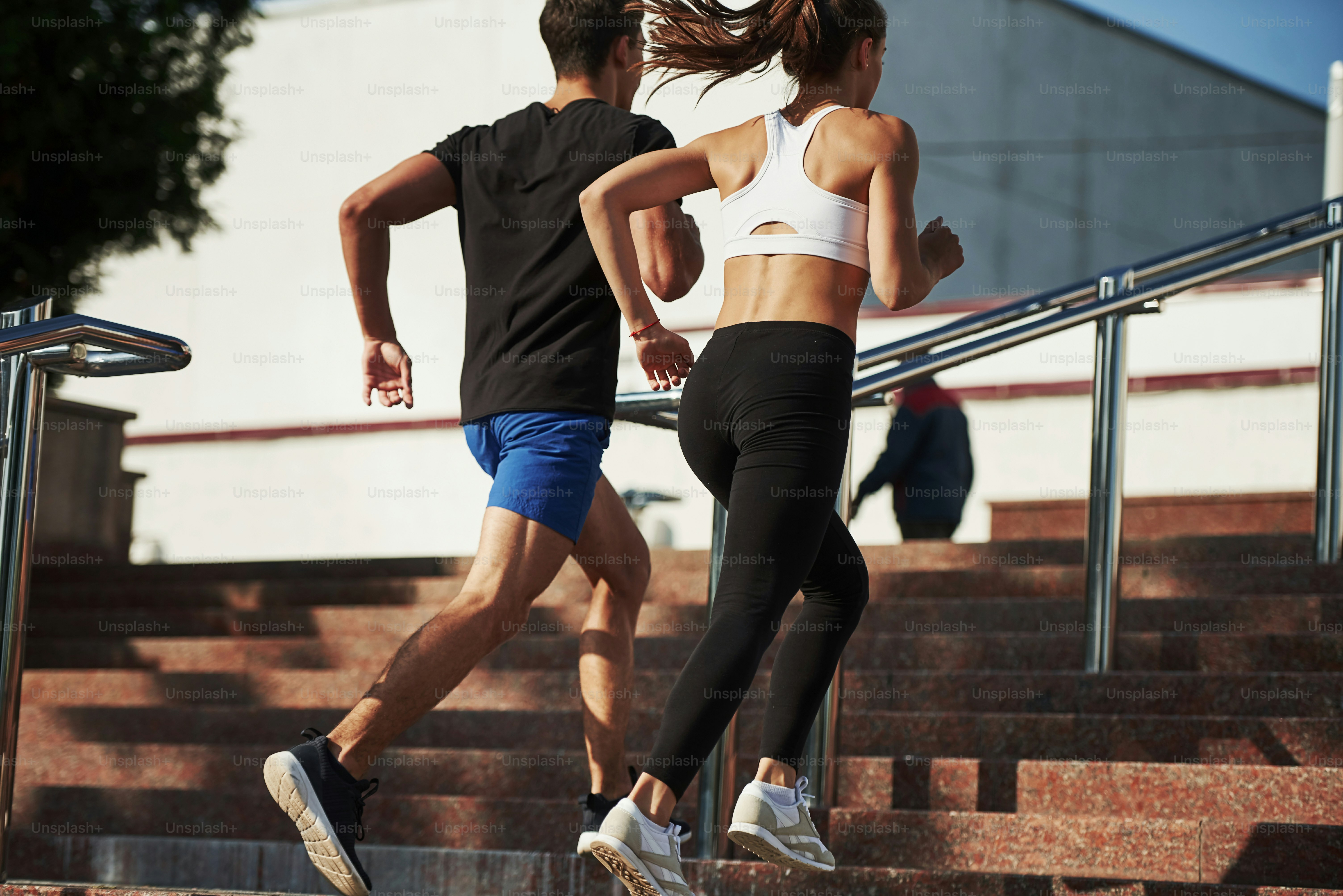 On the stairs. Man and woman have fitness day and running in the city at daytime.