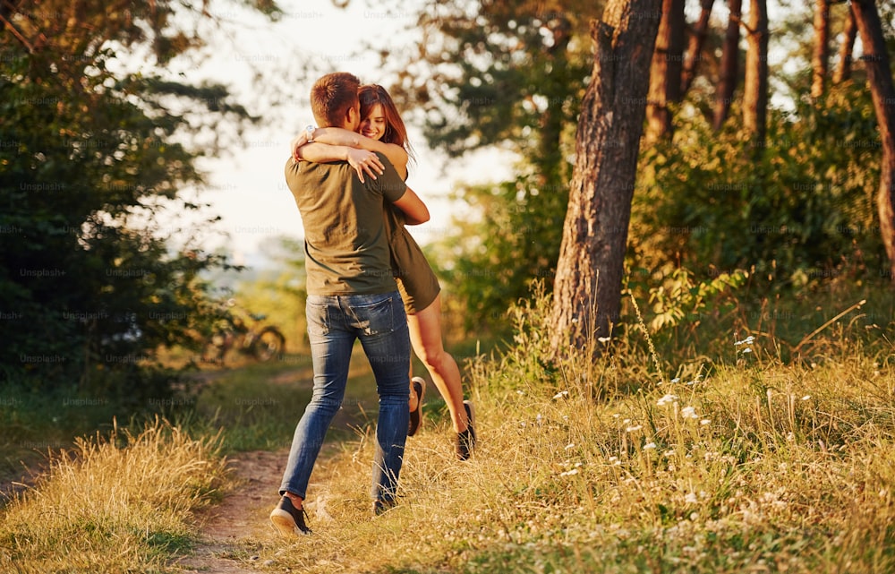 In love with each other. Beautiful young couple have a good time in the forest at daytime.