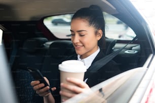 Portrait d’une femme d’affaires utilisant son téléphone portable sur le chemin du travail dans une voiture. Concept d’entreprise.