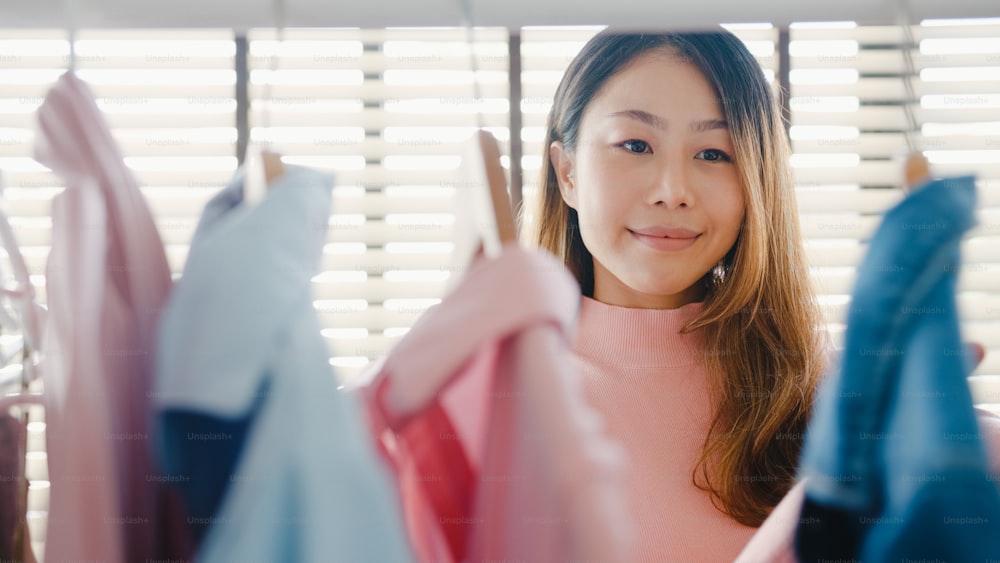 Schöne attraktive junge Asia-Dame wählt ihre Mode-Outfit-Kleidung im Schrank bei Haus oder Geschäft. Mädchen denken, was lässiges Hemd zu tragen ist. Umkleidekabine für Hausgarderobe oder Bekleidungsgeschäft.