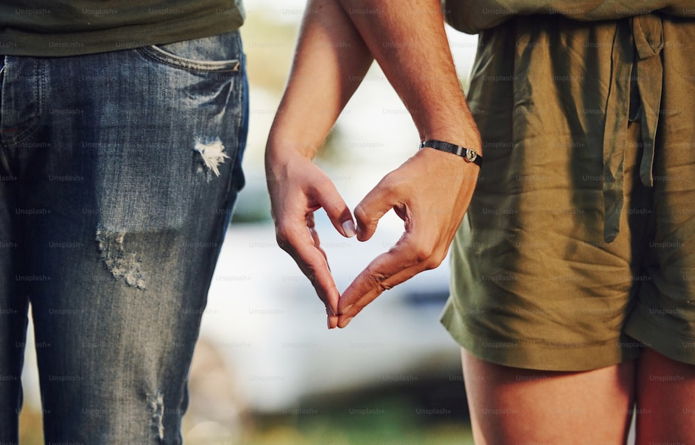 Fare il gesto del cuore e dell'amore con le mani. Giovane coppia si diverte nella foresta durante il giorno.