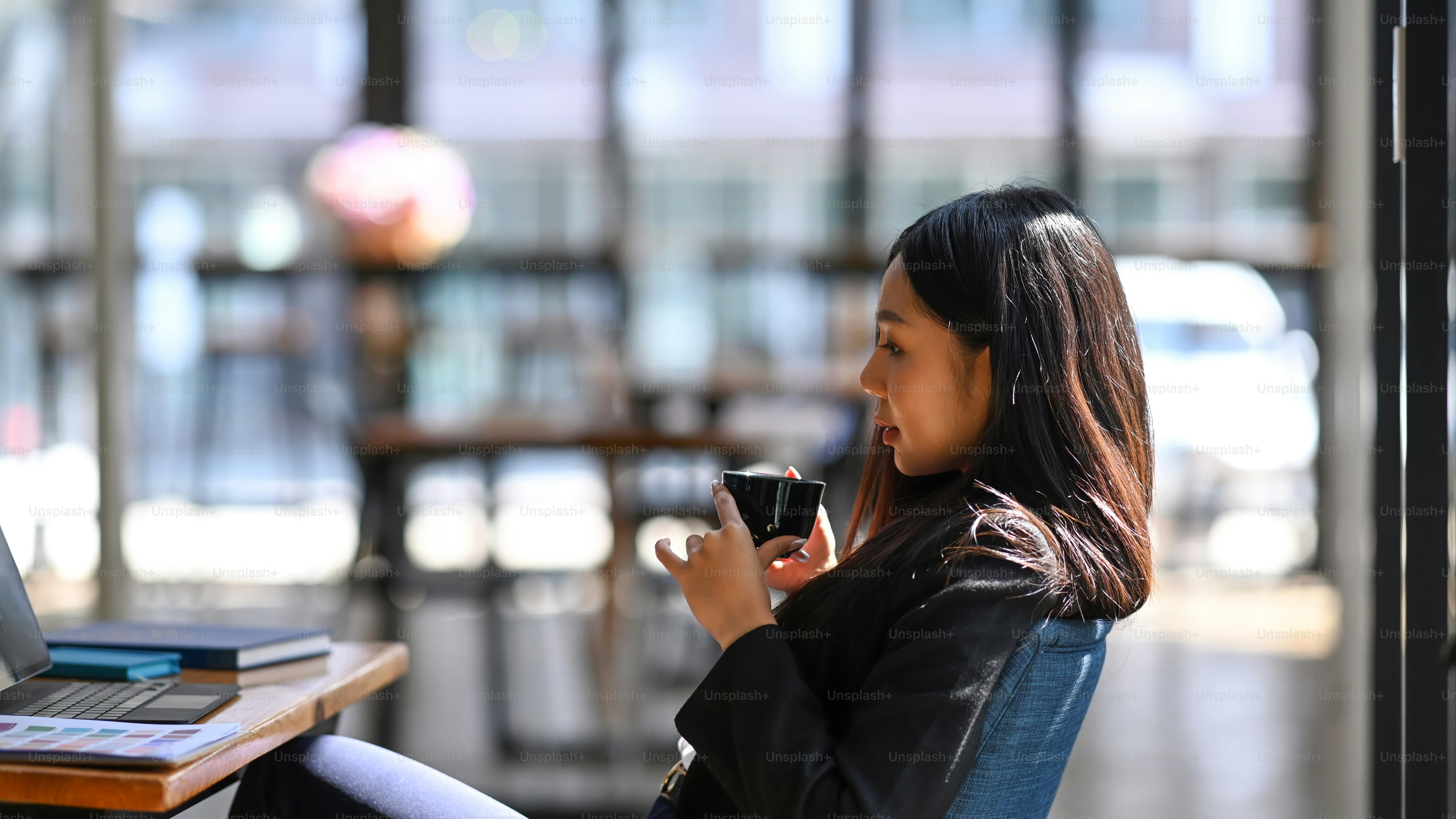 Side view of businesswoman taking a break and drinking coffee while sitting at her workplace.