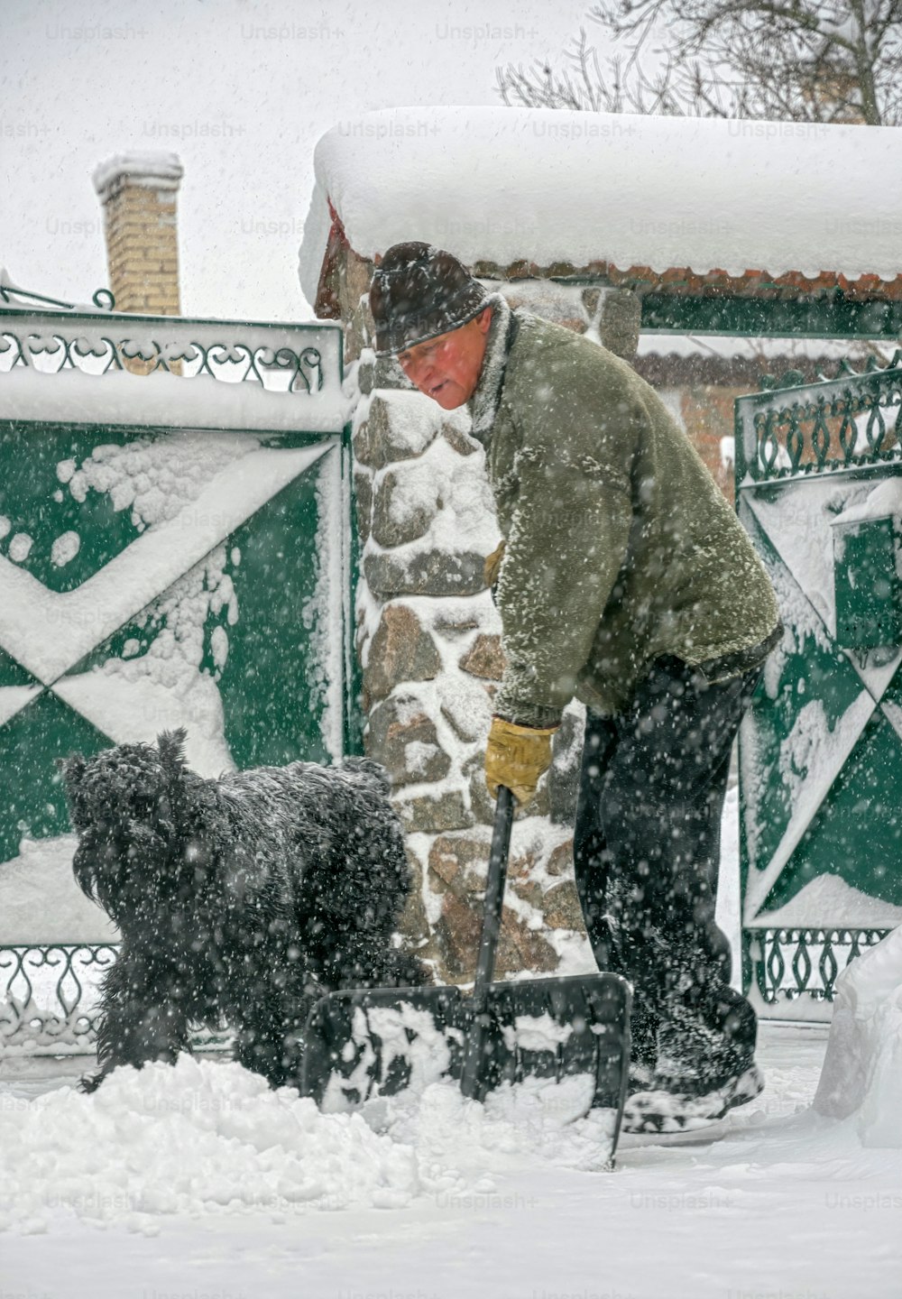 Uomo anziano con una pala in mano sgombera la strada dopo una forte nevicata. Uomo al lavoro stagionale