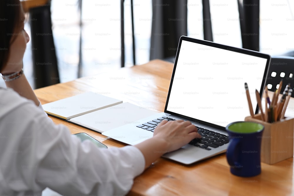 Businesswoman busy working with laptop on wooden office desk.