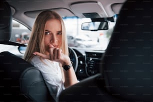 Si voltò di nuovo verso i cameramen sul sedile posteriore. Bella ragazza bionda seduta nella nuova auto con interni neri moderni.