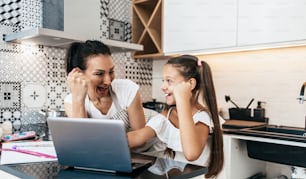 Young mother helping her daughter on e-learning session during Covid-19 pandemic crisis lockdown or quarantine. Illness prevention and new normal concept.