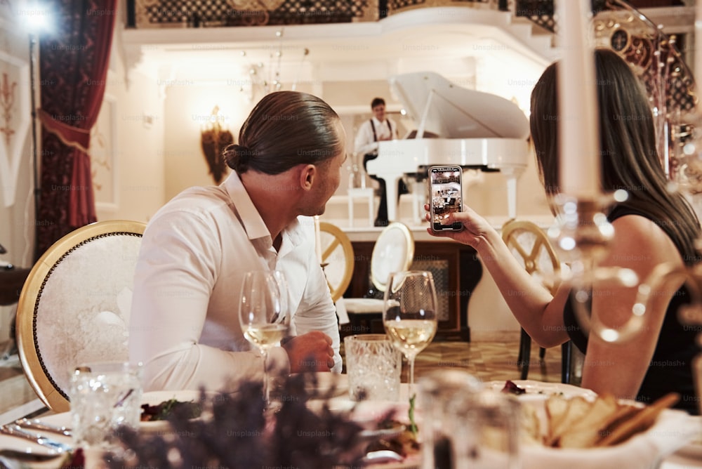 Conversation between pair and musician. Beautiful couple have romantic dinner in luxury restaurant at evening time.