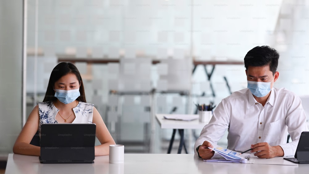 Image of business people wearing protective mask working together with modern devices in office.