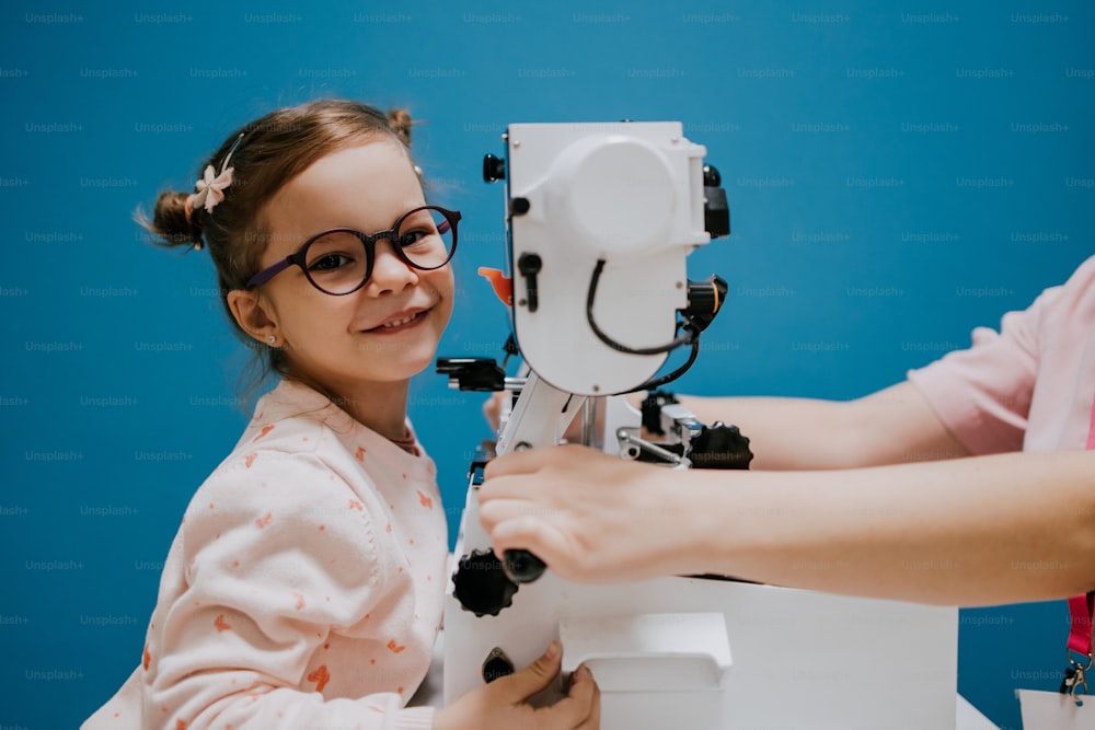 Schönes und entzückendes kleines Mädchen, das eine ophthalmologische Behandlung erhält. Augenarzt überprüft ihr Sehvermögen mit modernen Geräten.